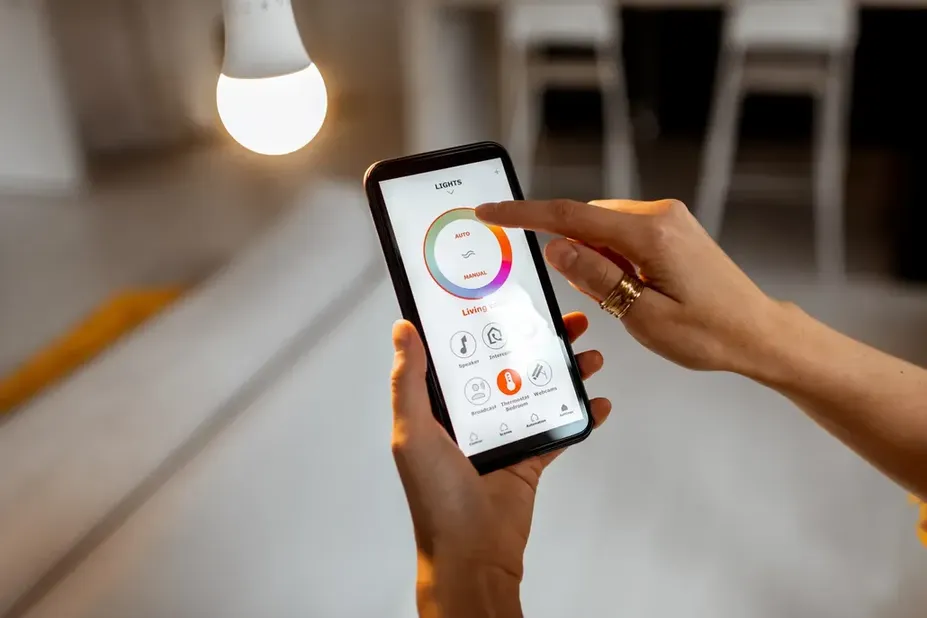 Aplicación móvil de eficiencia energética para iluminación Persona usando una aplicación de smartphone para regular la eficiencia energética de una bombilla inteligente