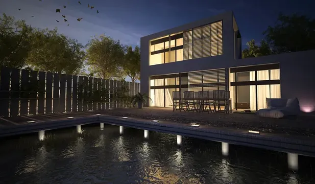 Vista nocturna de una casa moderna con terraza y piscina equipada con sistema de audio para exteriores en los alrededores