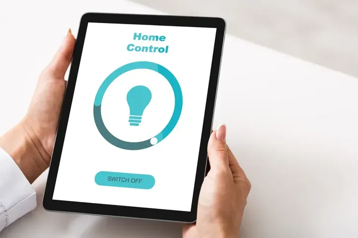 Dispositivo inteligente para la eficiencia energética en el hogar Manos sosteniendo una tablet con una interfaz de control digital enfocada en la eficiencia energética