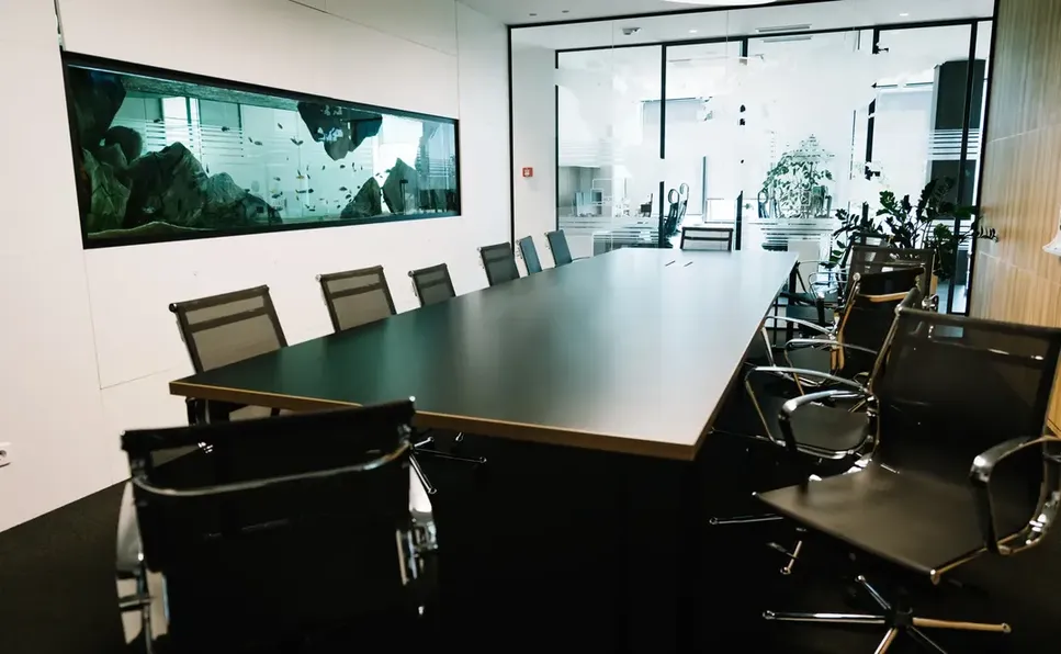 Salas de Juntas Inteligentes con Diseño Ejecutivo y Pecera Decorativa Salas de juntas inteligentes equipadas con mesa oscura, sillas ergonómicas y una gran pecera panorámica empotrada en la pared.