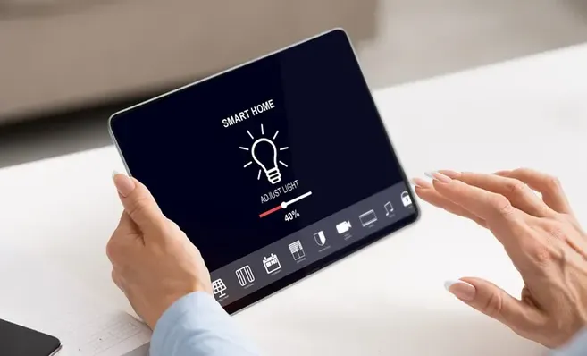 Manos interactuando con la pantalla de una tablet para gestionar los ajustes del control de iluminación en el hogar